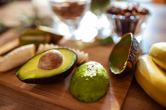 Close up of fresh avocado and banana slices on wooden cutting board in bright kitchen with natural light