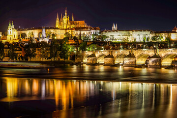Obraz premium This enchanting night view of Prague, Czech Republic, features the illuminated Prague Castle as a focal point, with the historic Charles Bridge