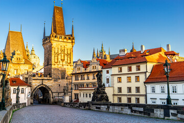 Fototapeta premium Prague, Czech Republic, in daylight, presents a picturesque scene from the Charles Bridge, looking towards the majestic Lesser Town Bridge Towers, with historic statues standing guard and colorful arc