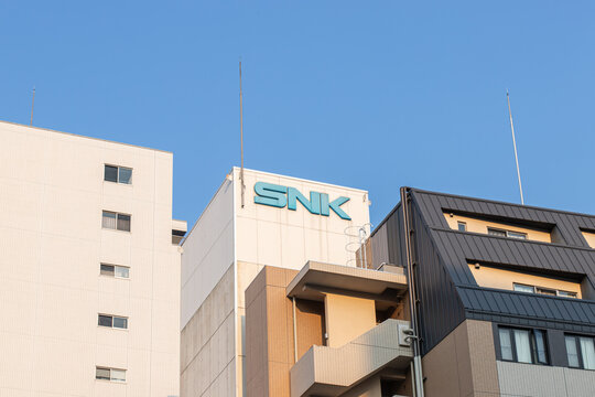 Suita, Osaka, JAPAN - May 22 2022 : SNK sign atop the company building in Suita, silhouetted against a clear blue sky at sunset.