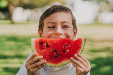 Ni&ntilde;o disfrutando y mordiendo una sandia fresca en el parque 