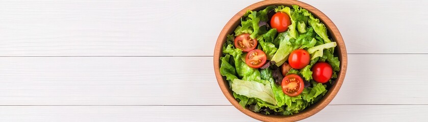 A fresh salad in a wooden bowl, featuring vibrant greens and cherry tomatoes, elegantly displayed on a white wooden background.