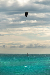 woman at sea rides a hydrofoil surfboard using a kite wing. Extreme sport, fast travel across the sea on a board