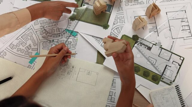 Architect and engineer consider or discuss about building construction using blueprint on table with architectural document, measurement tool and wooden block scatter around at office. Delineation.