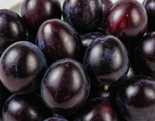 Fototapeta premium Glossy Black Plums Stacked Together in Close-up View