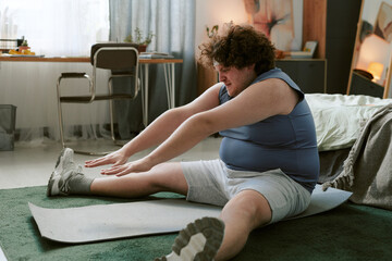 Obraz premium Person stretching on yoga mat in cozy bedroom setting with furniture and decorations, emphasizing fitness and flexibility