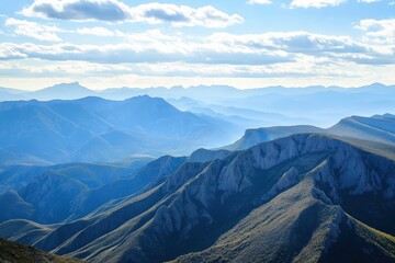 Fototapeta premium Majestic mountain range with layered peaks and rolling hills under partly cloudy sky