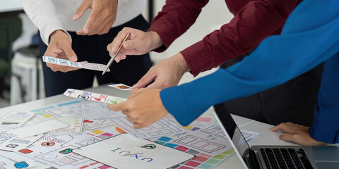 Collaboration and UX Design. Team members engaged in a collaborative UX design meeting, analyzing prototypes and sketching ideas together.