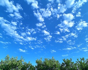 Obraz premium Blue sky with many small white clouds over green trees.