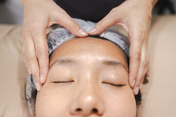 Naklejka premium Physical therapy, person receiving physical therapy facial treatment with hands gently massaging forehead, promoting relaxation and wellness
