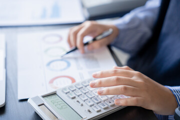 Asian businesswoman doing paper work with pen laptop calculator
