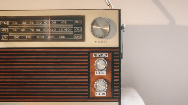 Authentic radio receiver from the 70s. Front view. Searching for the desired radio channel, adjusting the volume with a man's hand