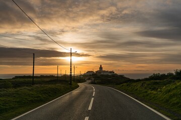 winding road to the lighthouse at cape roca in sintra. rays of the setting sun illuminate the path. suitable for photo wallpapers or screensavers
