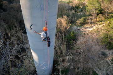 Rope access technician performing inspection and maintenance on industrial chimney