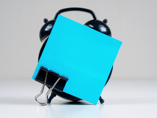 A blank reminder sticker and alarm clock inspire productivity, creating space for ideas and plans.