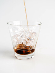 Pouring Cola with Ice in Glass on White Background