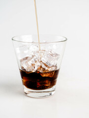 Pouring Cola with Ice in Glass on White Background