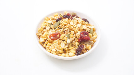Granola with oats, nuts, and dried fruits on bowl isolated on white background