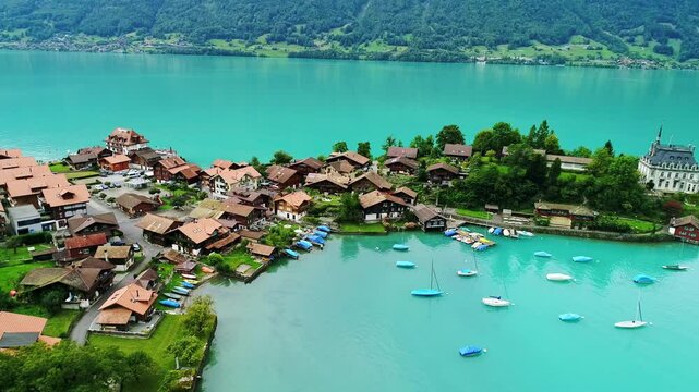 Peaceful Swiss lake village and boats in summer sun, dramatic wide aerial view