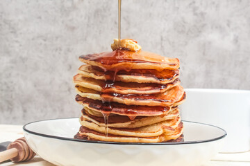 honey poured on a stack of pancakes on a plate