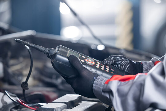 Auto mechanic using diagnostic tool for control battery lvl of car in workshop