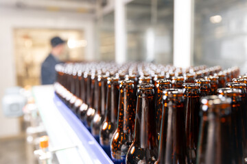 Beer bottling process in brewery factory with worker in background
