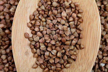 Top view of Buckwheat grain in wooden spoon, food background