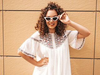 Beautiful smiling model with afro curls hairstyle dressed in summer white dress and sunglasses....