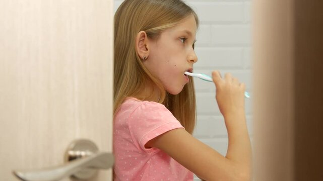 Child Brushing Teeth in Mirror, Young Kid Washing using Toothbrush, Blonde Girl in Bathroom, Teenager Healthcare