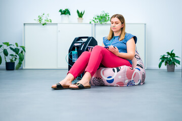 Oxygen therapy, supplemental oxygen. Young woman inhaling oxygen through nasal cannula attached to...