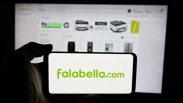 Stuttgart, Germany - 03-10-2025: Person holding cellphone with logo of Chilean retail company Falabella S.A. on screen in front of webpage. Focus on phone display.