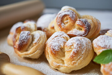 Sweet buns with powdered sugar on a wooden table. Selective focus.