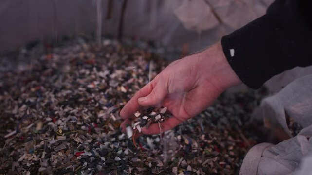 Fragments of plastic are pouring out of the hand, close up. Plastic waste and trash. Environmental pollution. Microplastic particles in the palm. Pieces of plastic in the oceans, garbage recycling