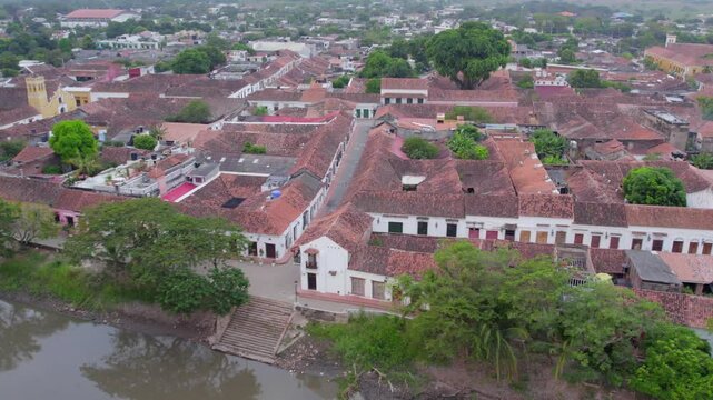 Counter rolling right over the Magdalena River, capturing the shimmering reflections of the trees on the water as the drone glides smoothly. In the background, the historic San Agust&iacute;n Convent.