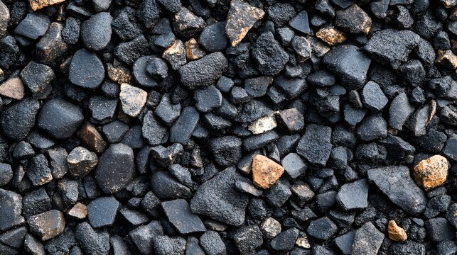 A high-resolution close-up texture photograph reveals a dense collection of dark gray and black pebbles mixed with a few smaller orange stones.