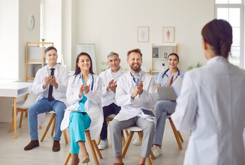 Doctor or nurse is leading a meeting and celebrating success with a diverse team of colleagues at a...