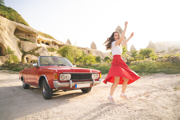 beautiful happy girl in a skirt posing near a retro car in the mountains of cappadocia