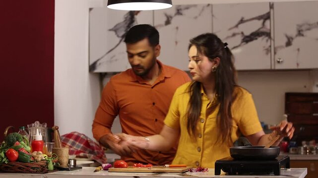 Indian couple preparing ingredients cooking meals together for family at kitchen counter