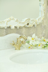 Bathroom background, interior detail. Gold faucet on white stone surface
