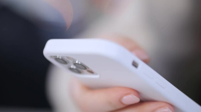 Person is holding a white iPhone with a case on it. The phone is turned on and the screen is lit up