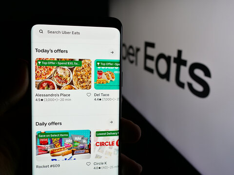 Stuttgart, Germany - 03-12-2025: Person holding web page with logo of US online food delivery company Uber Eats on screen in front of logo. Focus on center of phone display.