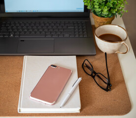 Home office desk workspace with laptop, coffee cup, blank sheet notebook, glasses and green plant  © boryanam