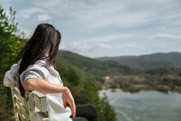 Fototapeta premium Traveler woman sitting high above a blue lake with stunning panoramic view .