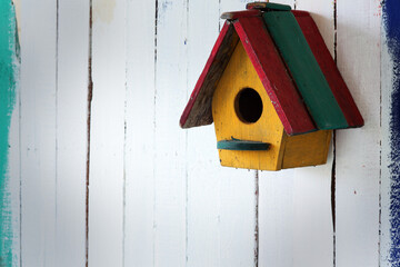 Colorful Wooden Birdhouse Hanging on Rustic White Wall Background