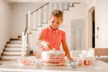 Little girl decorating cake with sprinkles in cozy home kitchen, preparing for birthday party