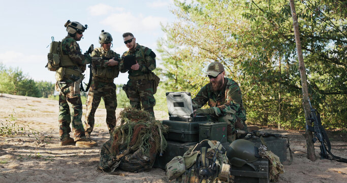 Servicemen get ready to defend territory, organizing gear for a forest expedition, studying maps, logging data into the system, and transmitting mission details to base.