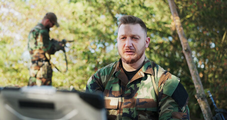 The serious army commander, positioned in the field, holds a video conversation with the head of...