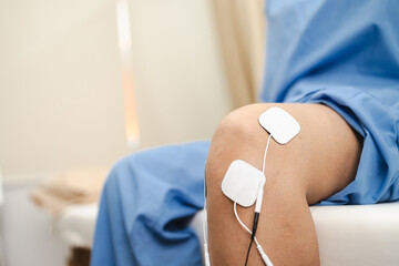 person receiving electrical stimulation therapy for physical rehabilitation on their knee, showcasing therapeutic process