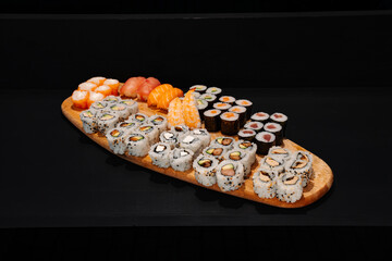 Creative minimalist display of assorted sushi rolls on a wooden platter against a dark backdrop, emphasizing vibrant colors and exquisite Japanese culinary art with a modern aesthetic.
