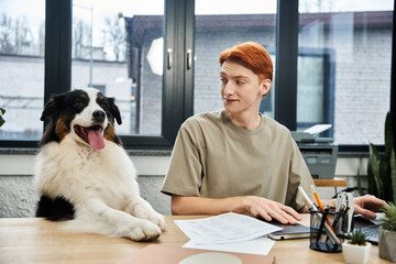 Young red haired man enjoys a productive day at work with his friendly office companion